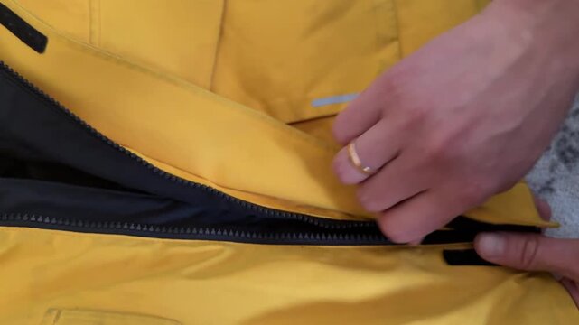 Hand closing zipper on yellow fabric bag