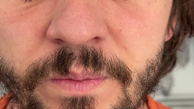 Close-up of a man slightly sniffling, nose tensing in a natural facial gesture