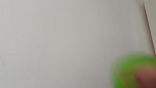 Hand throwing a green rubber ball against a wall