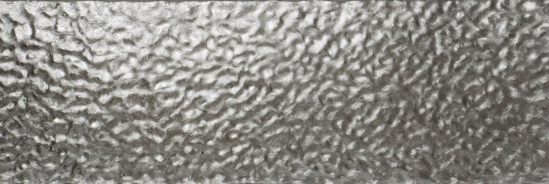 Silver hammered metal texture with swirling circular dents, shiny raised ridges, reflective gray surface, and abstract industrial background