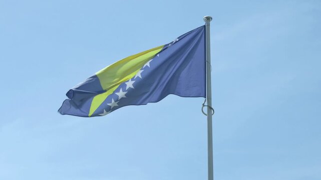 Bosnia and Herzegovina national flag waving against blue sky