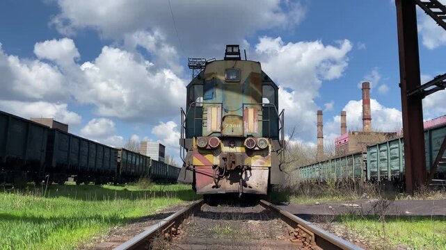 Old dirty diesel locomotive standing on railway tracks at a station. Static shot without camera movement. Concept of transportation, industrial infrastructure and railway logistics. 4K video.