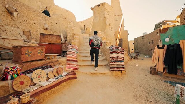a young man traveler walking alone exploring shali castle in siwa oasis in egypt at sunset, siwa oasis, Egypt.