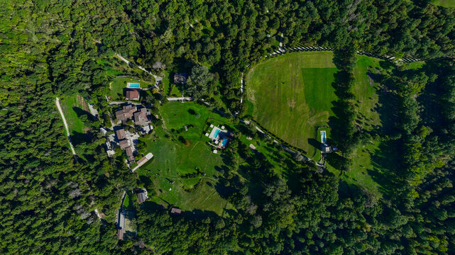 Poppi, Italy - 18 September 2025: Aerial view of Fattorie di Celli resort featuring stone villas, swimming pools, and manicured lawns surrounded by dense green forest.