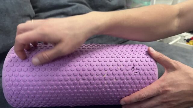 Fingers scraping across a pink textured foam roller
