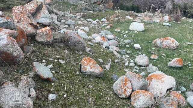 Large rocks rolling down grassy mountain slope among scattered stones and boulders, natural rockfall movement in rugged landscape, geological motion and erosion in wild outdoor terrain