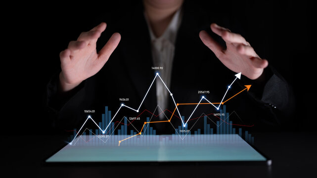 A business professional engages with digital financial graphs on a tablet, showcasing analysis, growth trends, and investment forecasts in a modern workspace. Scalp
