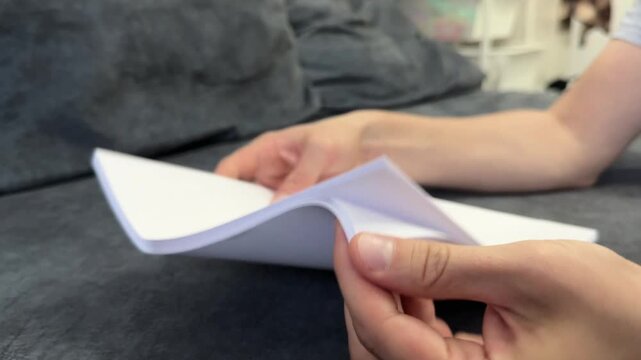 Hands flipping through a stack of white paper. Office or document-related task