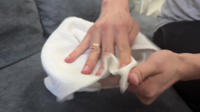 Hands drying a transparent glass plate using a white towel. Domestic cleaning routine, tableware care, and everyday kitchen hygiene at home