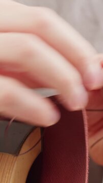 Man tailor repairing belt, artificial leather close-up. Craftsman making accessories made of genuine animal leather at workplace table. Professional atelier.