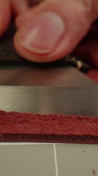 Man tailor repairing belt, artificial leather close-up. Craftsman making accessories made of genuine animal leather at workplace table. Professional atelier.