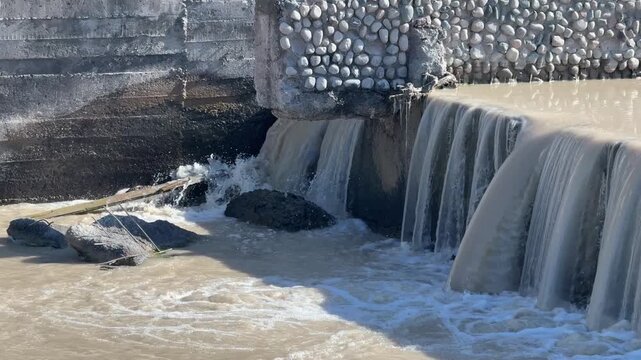 Waterfall flowing over concrete dam wall