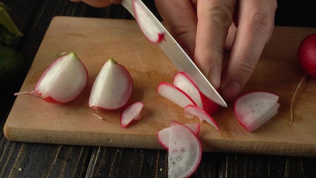 Hands slicing fresh radishes on a wooden cutting board, showcasing the progression of cutting techniques and visible kitchen elements in a home setting