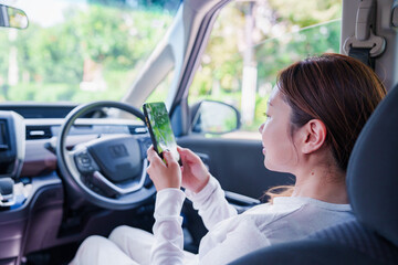 車の運転席で時間つぶしをする女性 © maroke