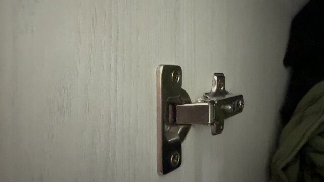 Hand opening wardrobe door with modern hinge mechanism. Close up of cabinet interior and furniture hardware, home organization concept