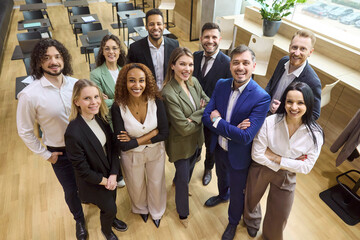 Business team professionals pose together showing teamwork. Diverse group in office smiles, showing...