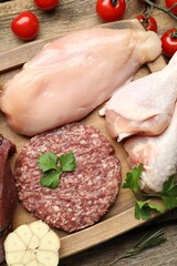 Naklejka premium Different raw meat products, tomatoes and spices on table, flat lay