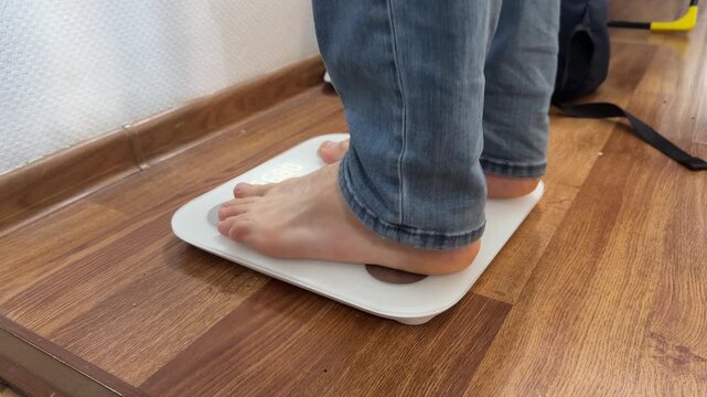 A man stands barefoot on a digital bathroom scale