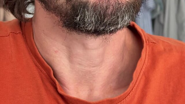 Close-up of a man&rsquo;s chin and neck while swallowing. Subtle movement of Adam&rsquo;s apple and beard texture