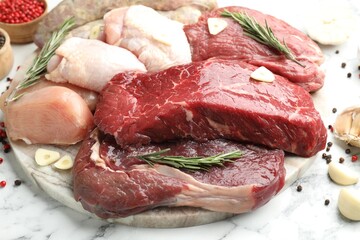 Fototapeta premium Different raw meat products and spices on white marble table, closeup