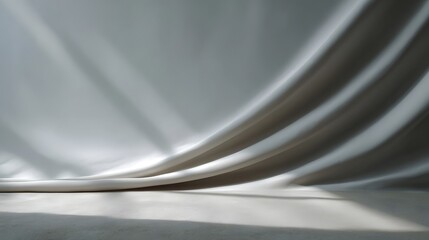 Gently draped fabric creating soft curves and dramatic shadows against a clean neutral backdrop