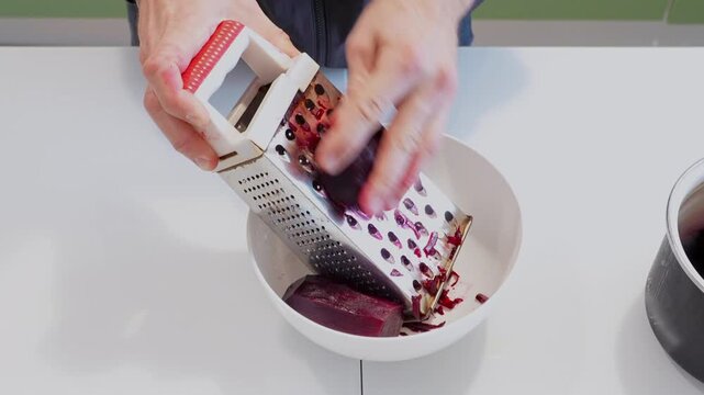 top view male hands grating boiled beet into bowl, kitchen food preparation process shredding cooked vegetable, preparing ingredients for salads and homemade meals with fresh beetroot