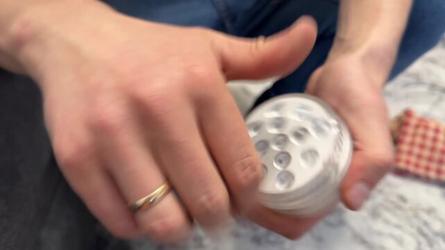 Hands adjusting a small LED light bulb or portable LED lamp. Close up of turning and setting lighting device for home use. Everyday household electronics and lighting setup concept