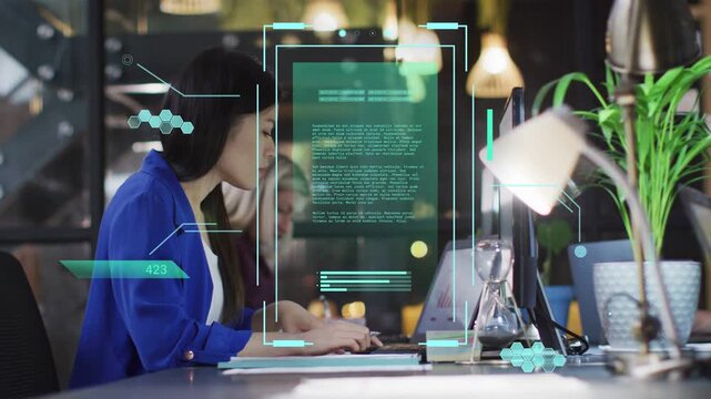 Blue blazer woman typing on laptop initiating AR overlay while peer leaning in reviewing tech chart