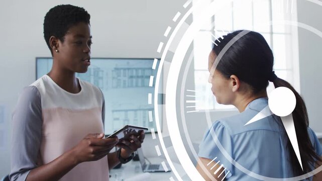 Woman presenting tablet, tapping phone at work, reviewing white circle overlay beside peer, smiling