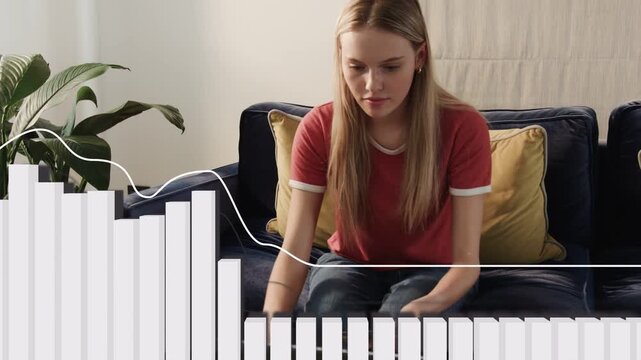 Woman sitting on couch, leaning in, pressing keyboard keys, audio visualizer reacting making music