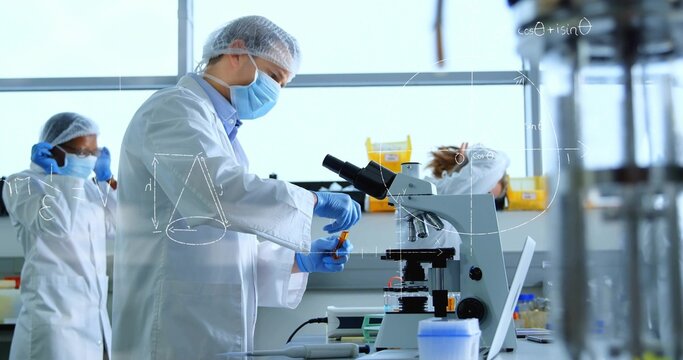 Handling scientist preparing samples at lab bench, wearing white lab coat, using microscope
