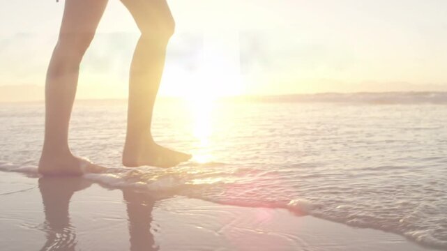 Woman walking shore toe making animated ripples  and  glare lighting horizon pausing to gaze for tra