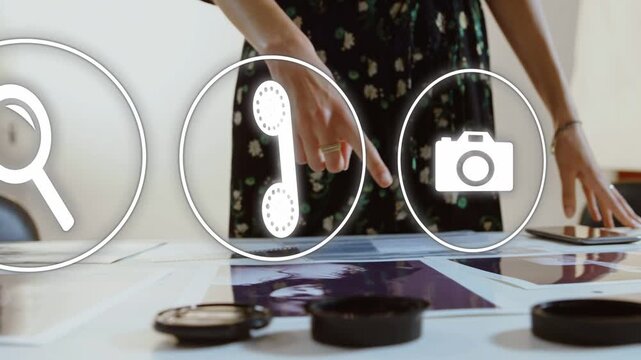 Female creative hovering hand over prints, activating faint icons and tapping phone selecting tools