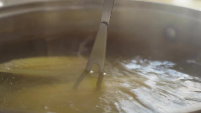 Close-up, kitchen fork pricking corn boiling in a pot to check for doneness