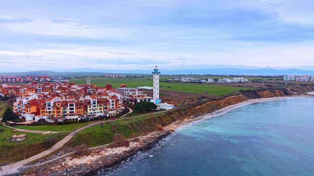Coastal landscape with resort lighthouse and steep cliffs. High angle aerial view of a seaside town with a lighthouse and erosion on the coastline.