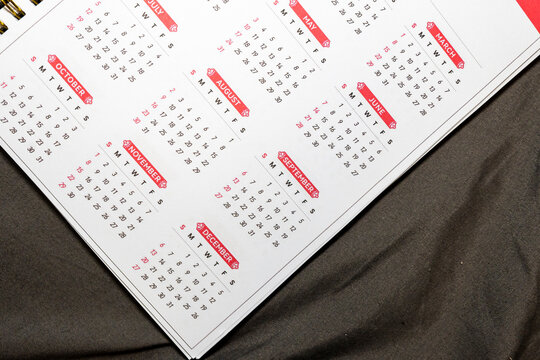 A close-up view of a printed calendar page featuring various months with highlighted dates, showcasing an organized layout and vibrant colors on a textured background fabric.