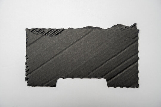 A dark gray piece of textured paper lies flat on a white background, showcasing subtle lines and patterns. This image serves as a versatile backdrop for design applications.