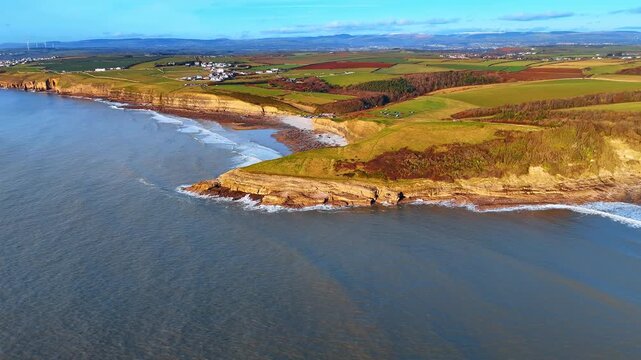 Panoramic aerial view of Southerndown village and Heritage Coast. Elevated perspective of the coastline, green fields, and distant settlements in the Vale of Glamorgan, Wales.