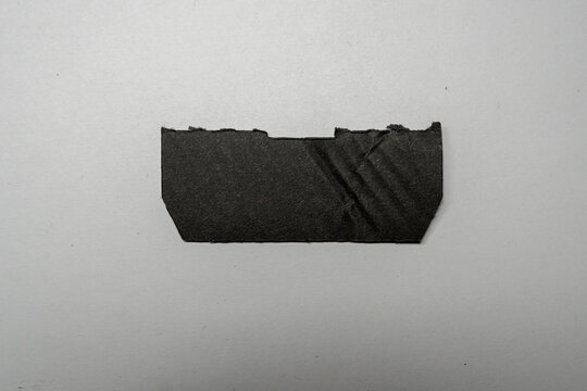 Handcrafted black paper strip on a light surface, showcasing a unique texture and shape, ideal for creative projects, branding, or arts and crafts applications.