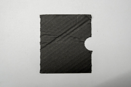 A rectangular piece of dark gray paper with a cutout corner sits on a plain white background. This versatile paper can be used for various creative and illustrative purposes.
