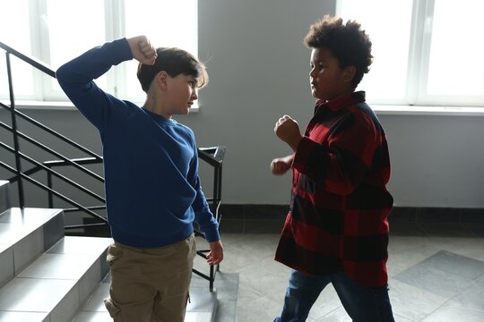Bullying. Boy fighting with his African American classmate in school