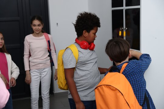 Boy bullying his African American classmate near lockers in school hallway