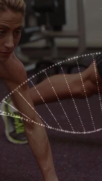 Vertical video: Woman gripping 4kg, rowing from plank in gym with helix particles showing core