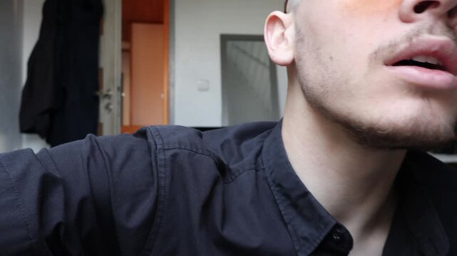 Young Vlogger Man with Orange Sunglasses Talking to Camera in Home Room, Influencer Recording Video Podcast or Video Call Concept.