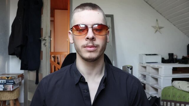 Young Caucasian Male Influencer with Tinted Sunglasses Talking Directly to Camera, Making Online Video Content or Virtual Meeting.