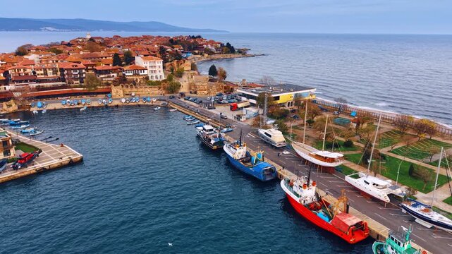 Diverse vessels stand at the shore in small marina. Harbor of beautiful Nesebar, Bulgaria from drone.