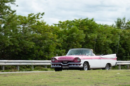 Dodge Custom 1957 Convertible from 1950s, dual tone pink-white vintage vehicle in Cuba, motion blur effect
