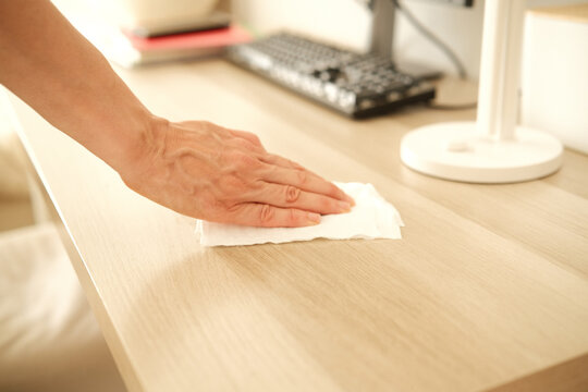 Woman hand wiping home office desk with wet tissue