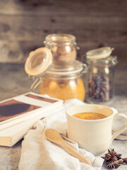 Fototapeta premium Turmeric latte golden milk with spices and books, cozy healthy lifestyle concept