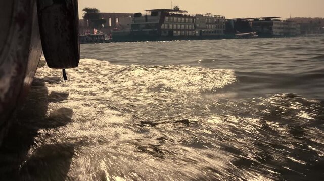 Boat cutting through water on the Nile, Luxor. Dynamic close-up shot from a moving motorboat on the Nile River in Luxor, Egypt. The camera is positioned just above the water
